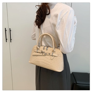 Detail of cream crocodile embossed handbag with metal buckle and dual strap functionality