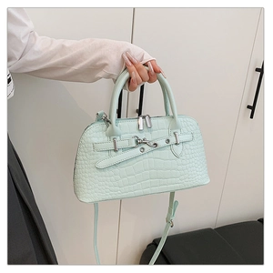 Close-up of mint green crocodile-embossed leather handbag with silver hardware and top handle
