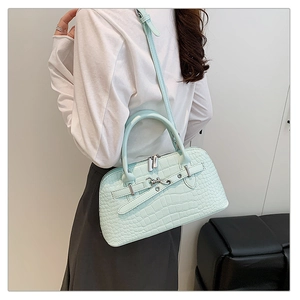Close-up of light blue crocodile embossed handbag with dual zippers and top handle