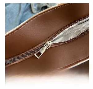 Macro shot of smooth silver zipper and herringbone lining on brown leather tote bag