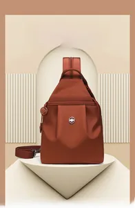 Dettaglio della borsa a tracolla marrone in tessuto oxford su piedistallo minimalista