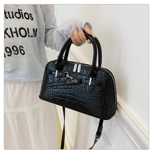 Detailed view of crocodile pattern faux leather handbag with silver hardware and handle