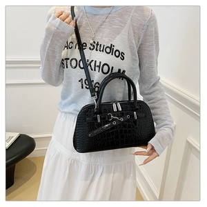 Detail of black crocodile texture handbag with silver hardware and model styling