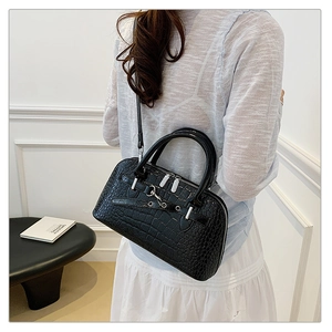 Close-up of black crocodile pattern leather handbag with silver zippers and hardware