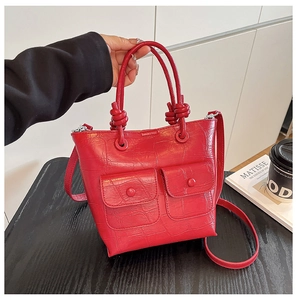 Detail of red crocodile pattern handbag with knot handles and double front pockets