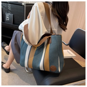 Detail der gestreiften Canvas-Tasche mit gewebter Textur und breiten braunen Trägern