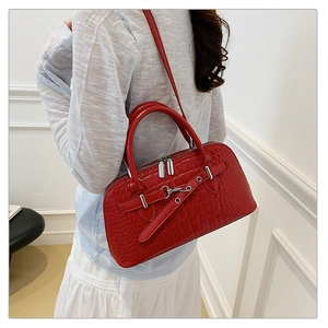 Detail shot of a red crocodile embossed handbag with glossy finish and silver hardware