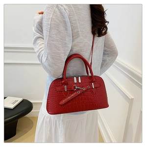 Detail of red crocodile embossed shell bag showing sleek leather texture and metal buckles