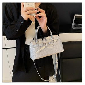 Macro detail of silver crocodile embossed handbag with metal hardware and top handles
