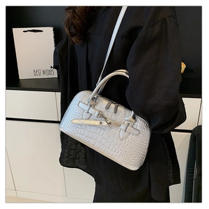 Silver crocodile pattern handbag with top handles and shoulder strap shown by a model