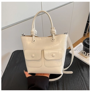 Detail of cream white faux crocodile leather handbag featuring dual front flap pockets