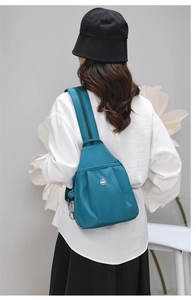 Dettaglio della borsa a tracolla antifurto verde acqua in nylon con pieghe e logo argento