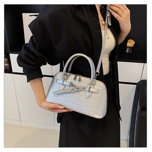 Close-up of silver crocodile embossed texture and metallic turn-lock on the handbag