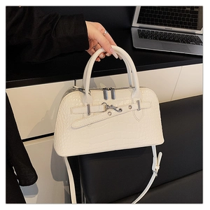 Detail of white crocodile embossed handbag featuring silver buckle and reinforced handles