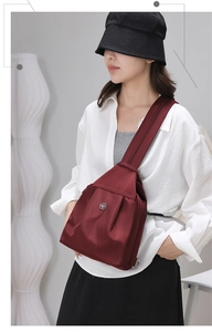 Dettaglio borsa a tracolla in nylon rosso scuro con design a pieghe e chiusura in metallo