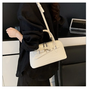 Close-up of white crocodile pattern embossed handbag with metallic buckles and office decor