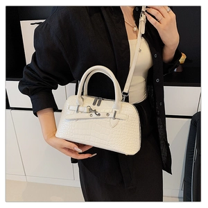 White crocodile pattern handbag with silver lock shown being carried by a model
