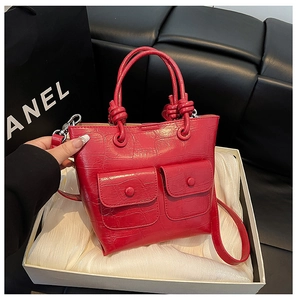 Detail of red crocodile pattern handbag with knot handle and shoulder strap in gift box