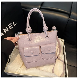 Detailed pink crocodile embossed handbag showing front double pockets and adjustable strap