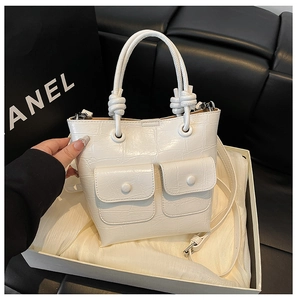 Detail of white crocodile pattern bucket bag showing textured leather and double front pockets