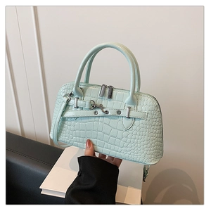 Detail of mint green crocodile embossed faux leather bag with stylish metal buckle