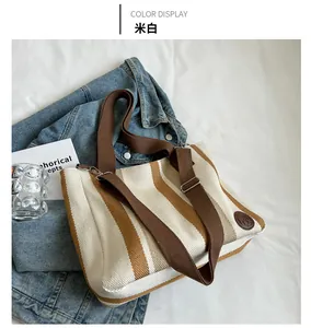 Detail of striped canvas tote with brown straps laid on denim and white bedding background