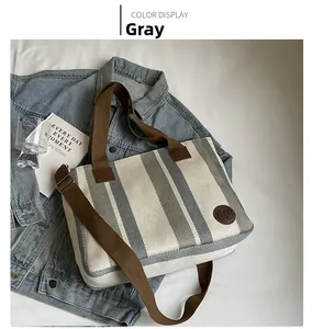 Detail view of retro striped canvas tote bag with woven handles and brown leather logo