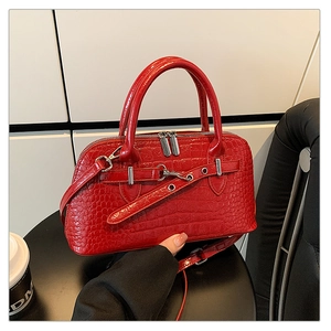 Close-up of red crocodile embossed handbag with silver metal buckles and dual zippers