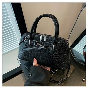 Detailed macro view of black crocodile embossed leather handbag with silver metal zippers