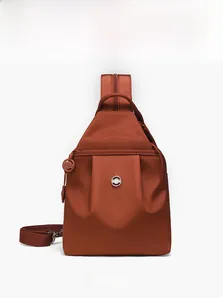 Dettaglio frontale borsa pettorale in nylon rosso mattone con design plissettato e logo