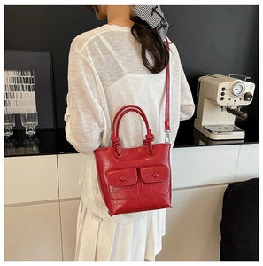Detail of red crocodile texture handbag with unique knotted handle and dual front pockets