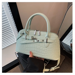 Close-up of mint green crocodile embossed handbag with silver metal buckle and shoulder strap