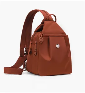 Vista laterale dello zaino monospalla in nylon rosso mattone impermeabile con scomparti zip