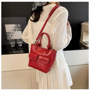Detail of red crocodile texture handbag with dual front pockets and shoulder strap