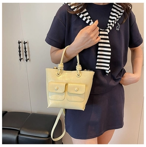 Detail of yellow crocodile embossed handbag featuring knot handle and front pockets