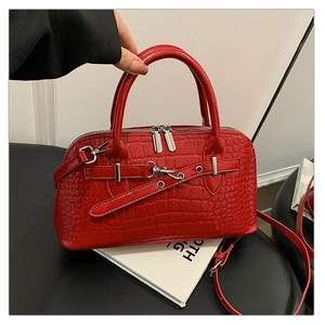 Detail of red crocodile pattern handbag with dual zippers and metallic buckle