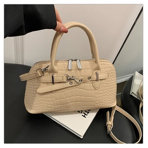 Close-up of beige crocodile pattern handbag featuring silver zippers and sturdy top handle