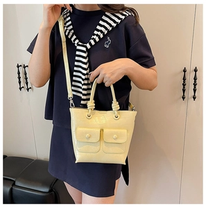 Lifestyle shot of a pale yellow faux crocodile handbag paired with a dark dress
