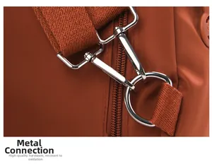 Dettaglio del gancio in metallo lucido e tracolla in nylon marrone dello zaino