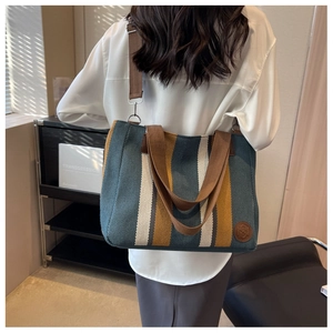 Detail of striped canvas tote bag with brown straps and logo on durable material