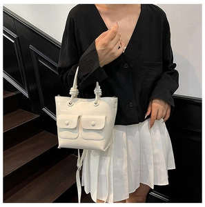 Close-up of cream white crocodile texture handbag featuring knotted handle and pockets