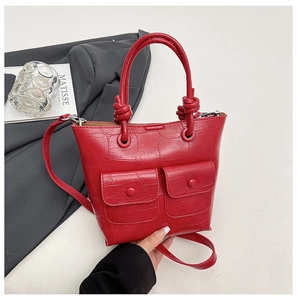 Detail of red crocodile pattern handbag with dual pocket flap and knotted handle decoration