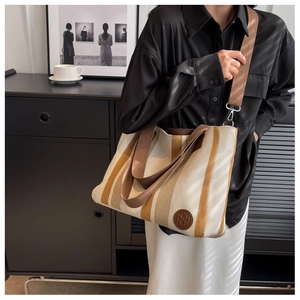Close-up of canvas tote bag with brown stripes and round embossed leather logo