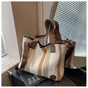 Detail of striped canvas tote bag with adjustable shoulder strap and leather logo patch