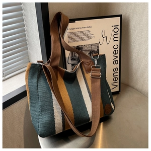 Detail of striped knitted tote bag with wide brown shoulder strap and textured fabric