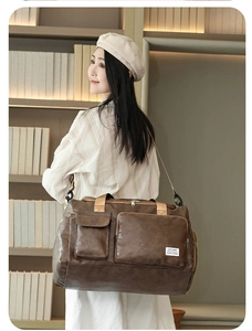 Detail of a dark coffee textured travel duffel bag with shoulder strap in home setting