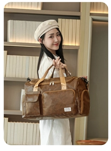 Detail of the large brown leather sports travel bag with textured front pocket and straps