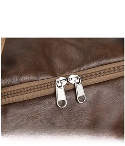 Detail of premium brown textured leather duffel bag featuring a dual metal zipper closure