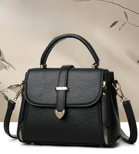 Détail d'un sac à main en cuir grainé noir avec boucle cœur dorée et anses rondes