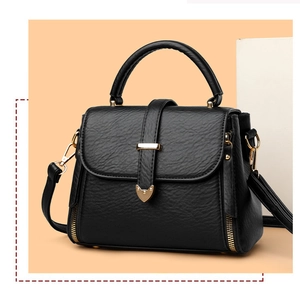 Détail du sac en cuir noir texturé avec fermoir cœur doré et finitions sur podium moderne